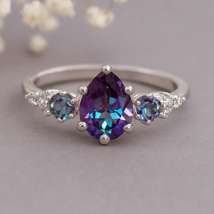 Silver ring with purple and blue gemstones on a soft gray background