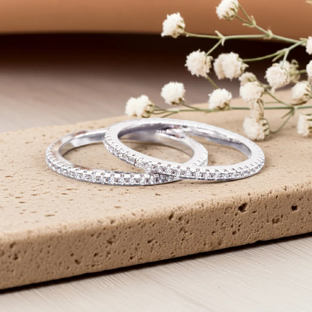 Two silver rings on a textured surface with white flowers in the background