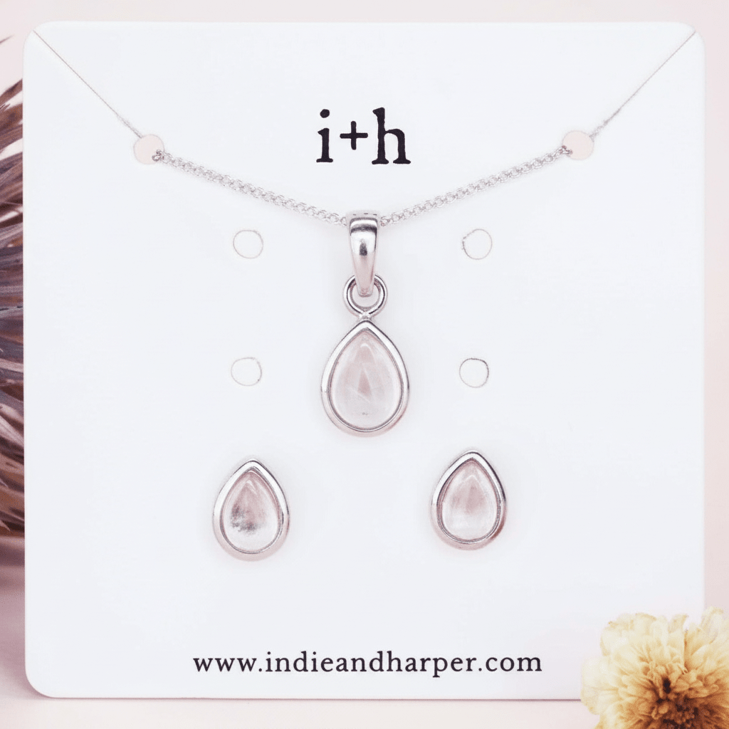 Silver teardrop necklace and earrings set on a display card with 'i+h' branding, featuring a website URL.