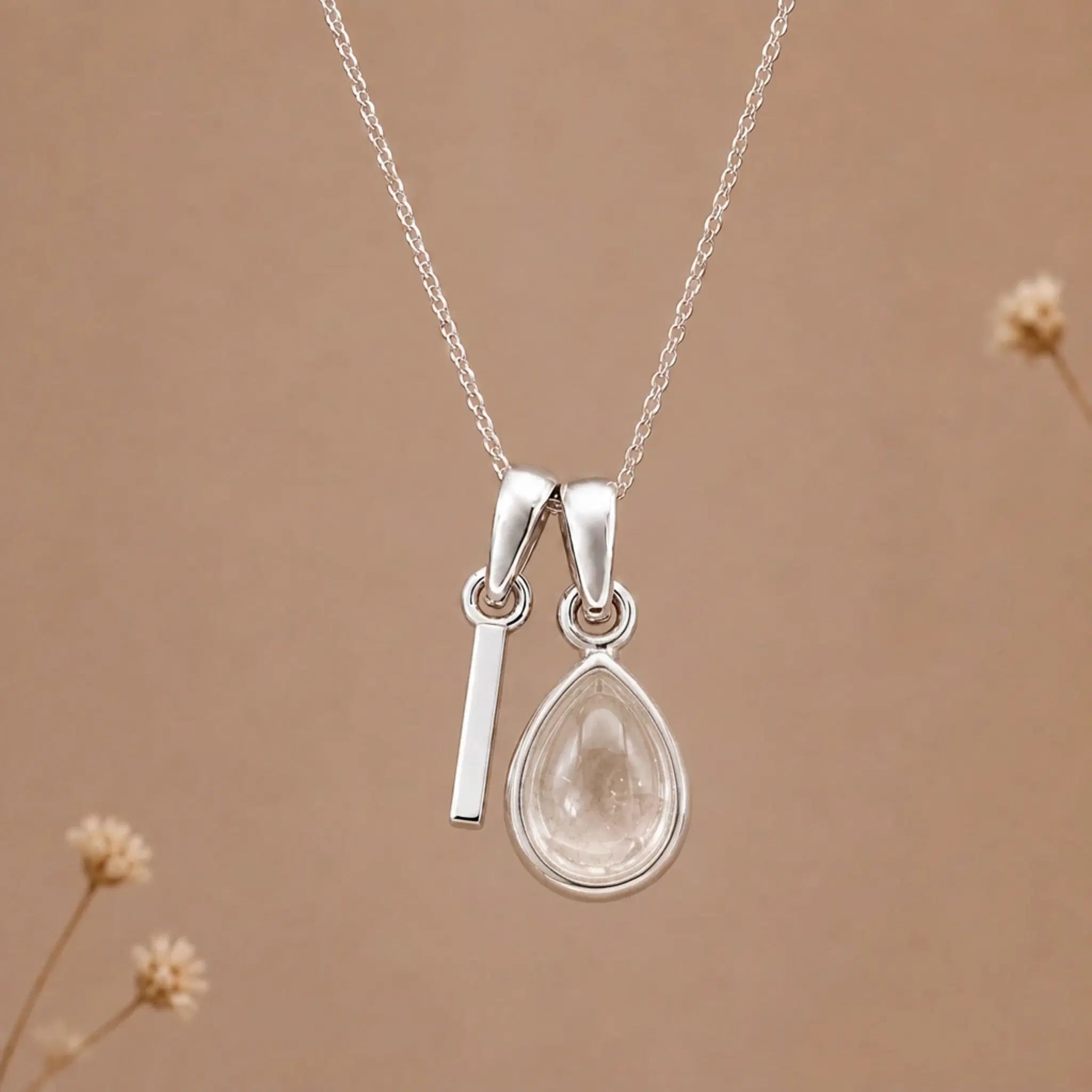 sterling silver initial i april birthstone natural clear quartz pendant necklace against a dark warm beige background