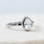 side view of a Sterling Silver April Birthstone Ring with a teardrop-shaped natural Clear Quartz gemstone on awhite background