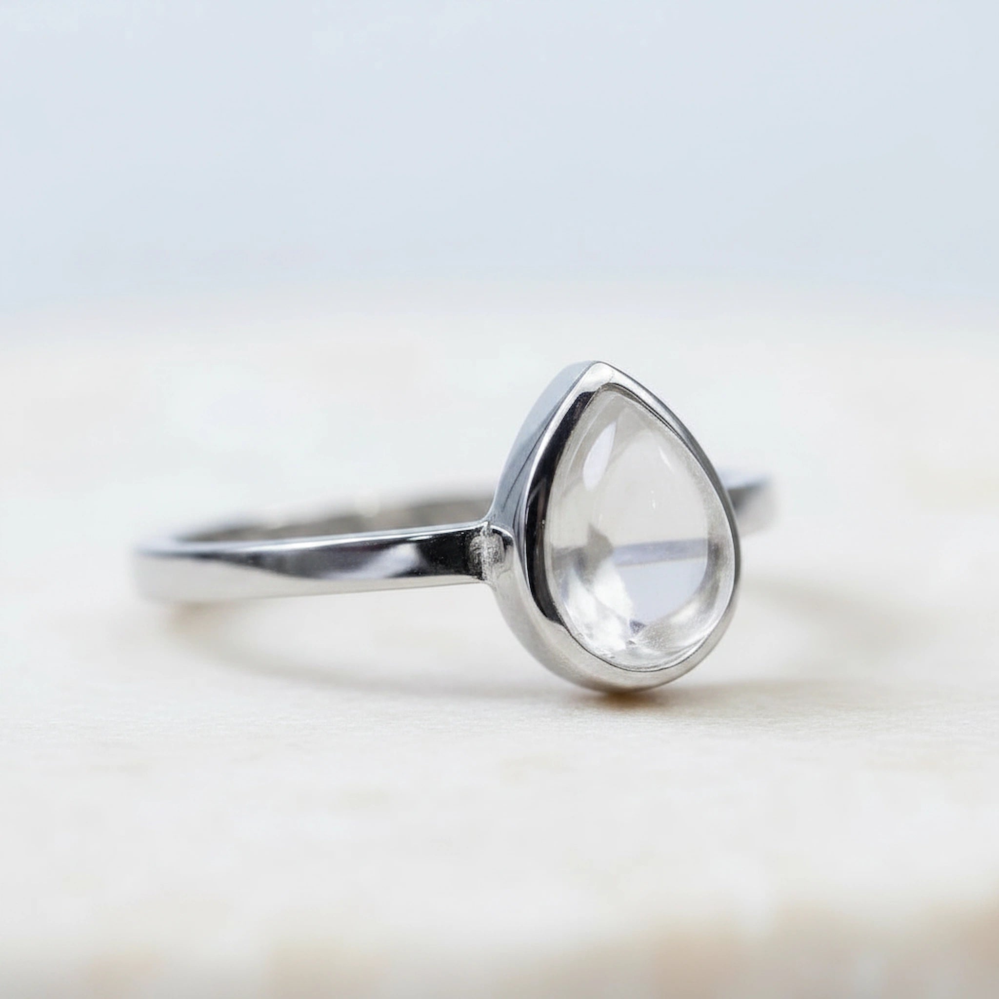 side view of a Sterling Silver April Birthstone Ring with a teardrop-shaped natural Clear Quartz gemstone on awhite background