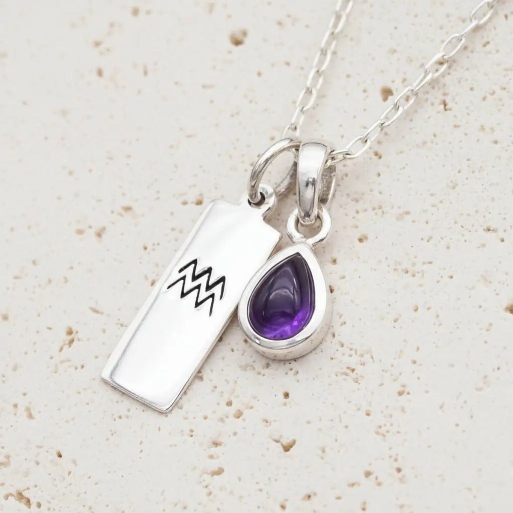 Silver Aquarius zodiac pendant and february Birthstone amethyst pendant on a Sterling Silver Necklace on a stone surface
