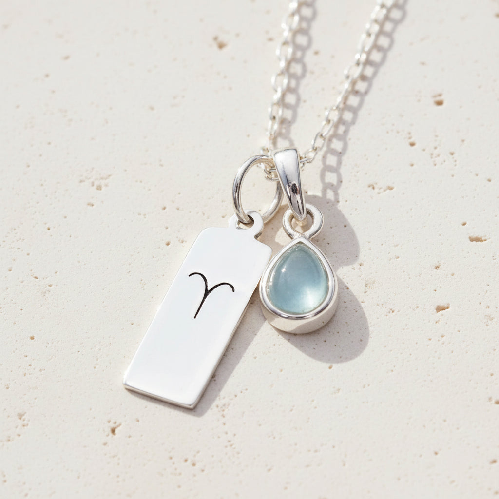 Sterling Silver Aries pendant and march Birthstone aquamarine pendant on a stone surface 