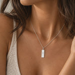 close up of a woman wearing a silver aries necklace with rectangle pendant engraved with aries zodiac star sign line glyph symbol