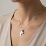 Sterling Silver April Birthstone necklace with a pear-shaped Herkimer Quartz pendant and a Aries zodiac pendant being worn