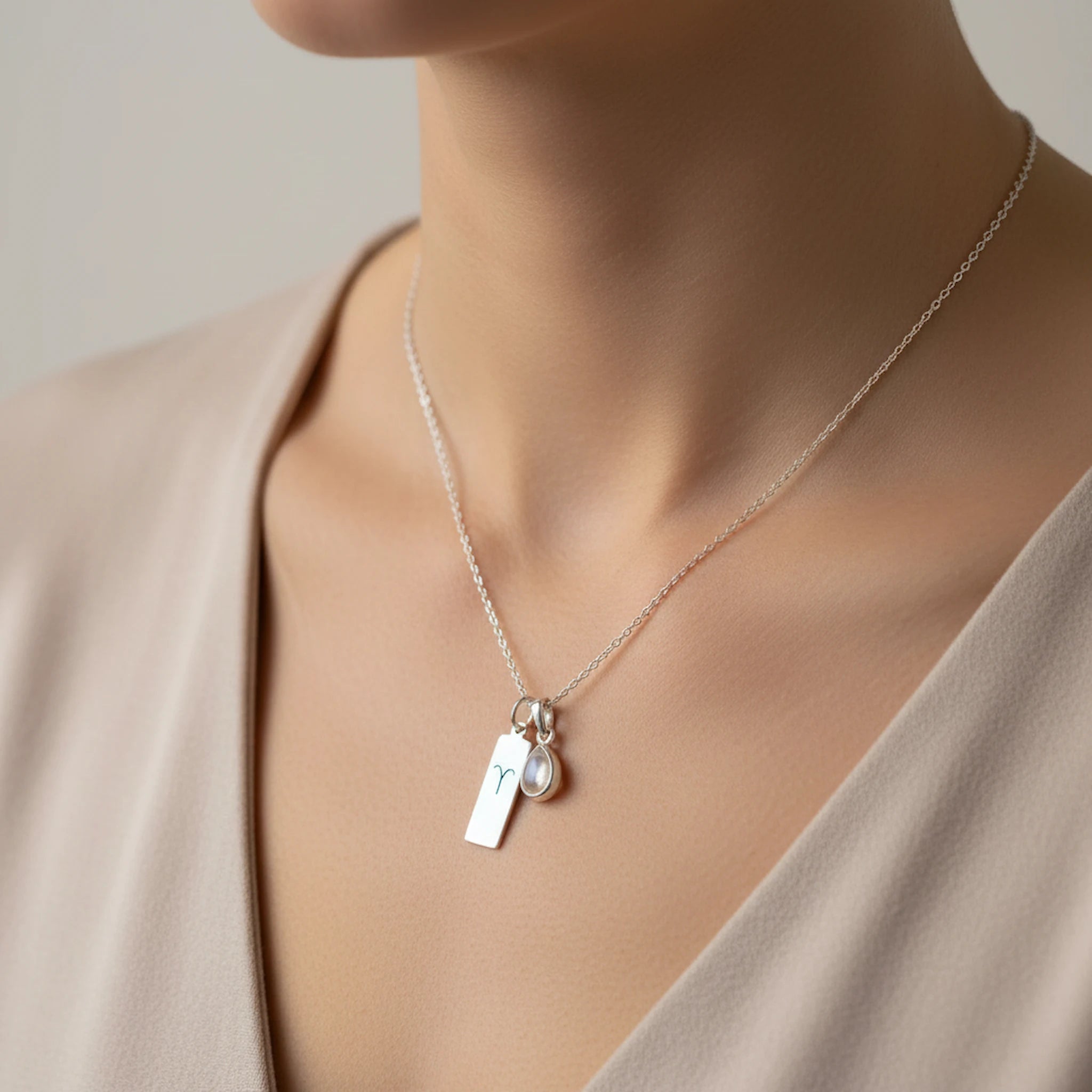 Sterling Silver April Birthstone necklace with a pear-shaped Herkimer Quartz pendant and a Aries zodiac pendant being worn