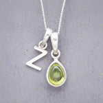 sterling silver double pendant necklace with a green teardrop august birthstone peridot pendant and uppercase letter Z pendant on a grey background