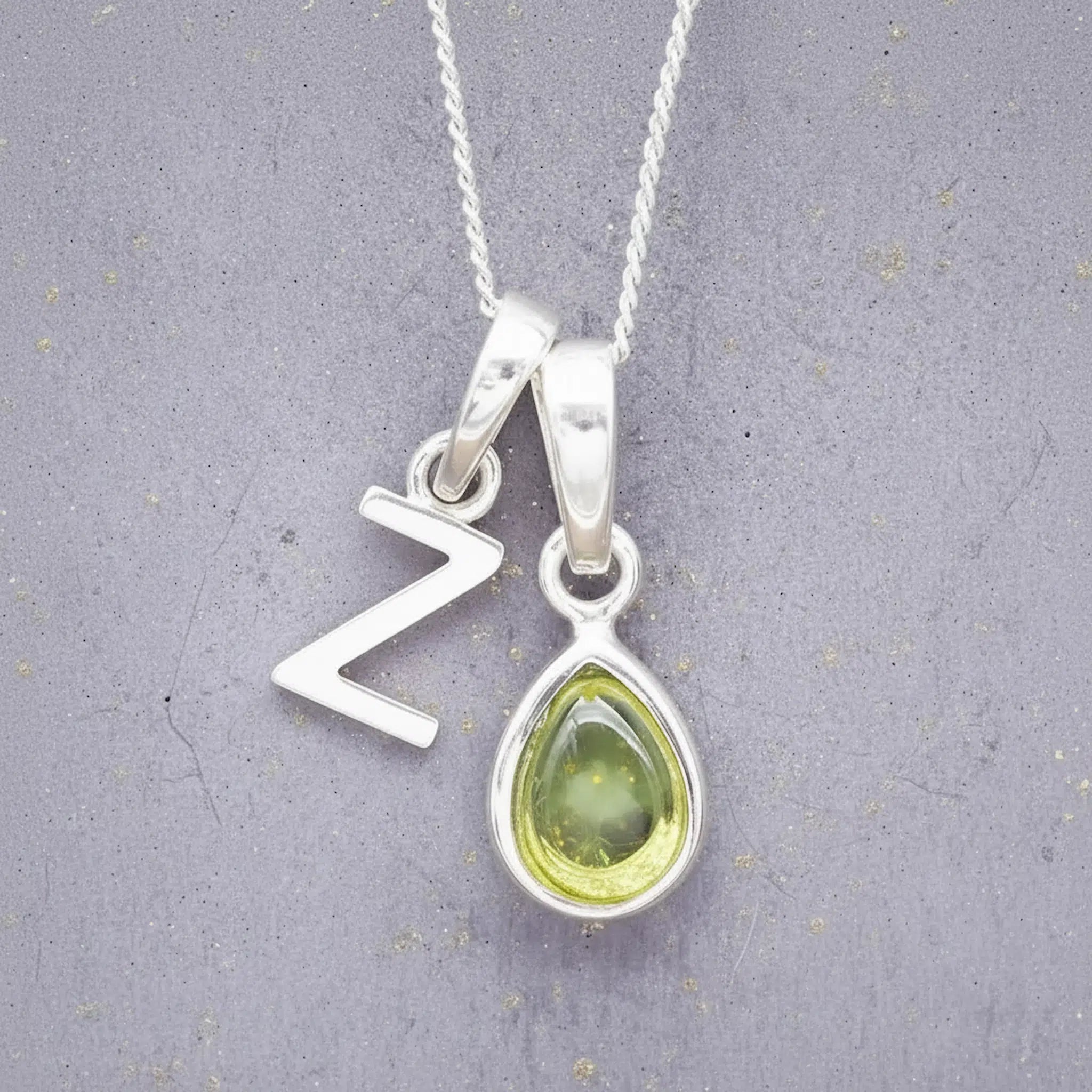 sterling silver double pendant necklace with a green teardrop august birthstone peridot pendant and uppercase letter Z pendant on a grey background
