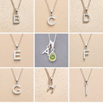 Collection of silver letter necklaces A to I on a beige background, as initial options to customise August Birthstone Peridot Necklace.
