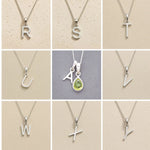 Collection of silver letter necklaces R to Y on a beige background, as initial options to customise August Birthstone Peridot Necklace.