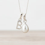 Sterling Silver necklace with 'B' initial pendant and teardrop-shaped mother of pearl charm on a light background