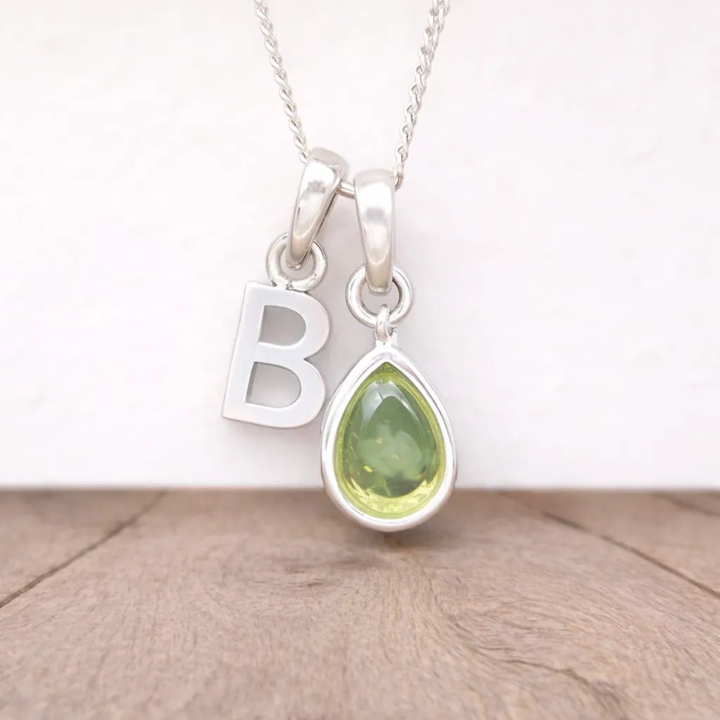 Silver Necklace with a green peridot teardrop pendant and letter 'B' charm on a white background.