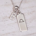 sterling Silver necklace with a libra zodiac pendant and a 'B' initial pendant on a light wooden background