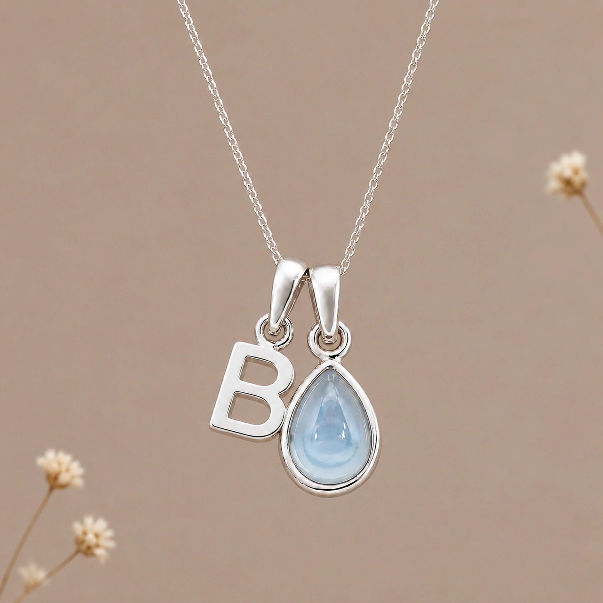 Sterling silver initial B and November natural blue topaz necklace on a taupe background with sparse ivory flowers