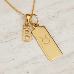 Gold necklace with 'B' pendant and Taurus zodiac symbol on a light background
