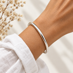 Silver minimalist classic bangle bracelet worn on the wrist with a white linen sleeve