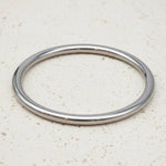 Silver bangle on a beige textured surface