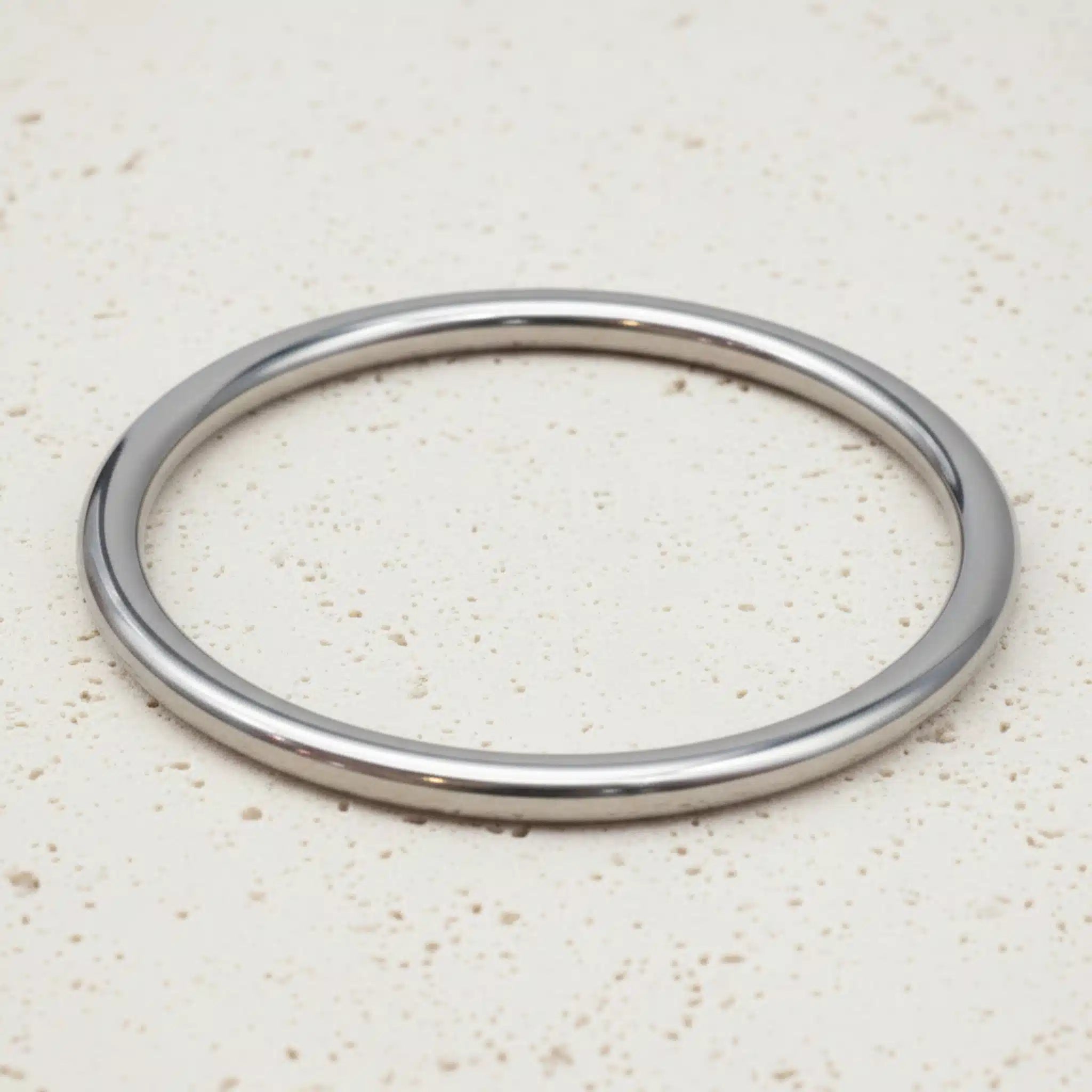 Silver bangle on a beige textured surface