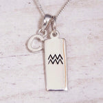 Sterling Silver C Initial and Aquarius Necklace on a fine silver chain against a light wooden background