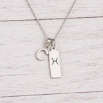 sterling silver C initial Pisces Necklace on a fine silver chain against a light wooden background