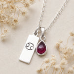 sterling silver necklace with a teardrop july birthstone ruby pendant and cancer line glyph pendant.