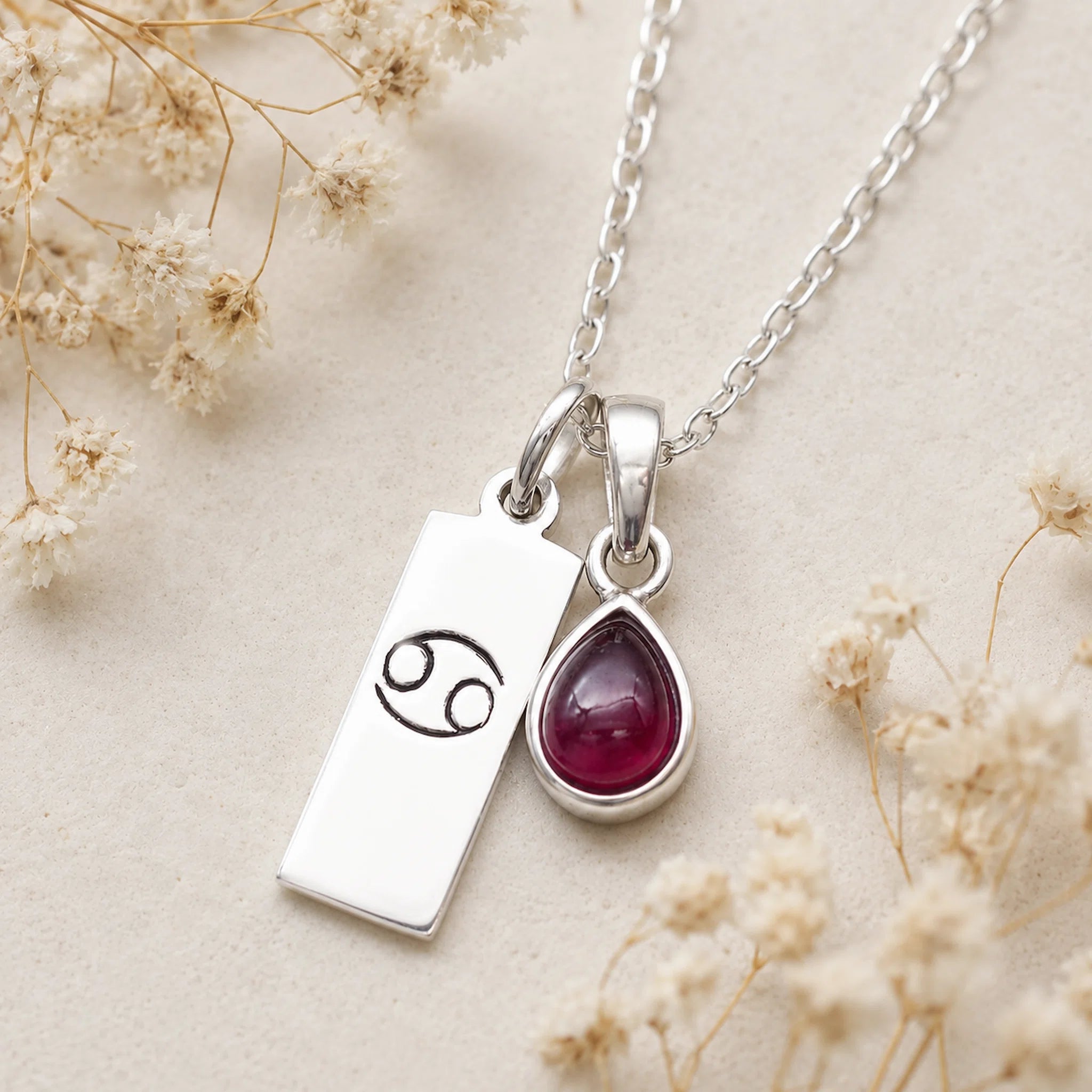 sterling silver necklace with a teardrop july birthstone ruby pendant and cancer line glyph pendant.