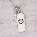 Indie and Harper personalised silver Cancer zodiac necklace with a hand-carved star sign symbol and initial charm on a 925 sterling silver necklace chain