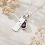 Sterling Silver necklace with a teardrop-shaped january birthstone natural garnet gemstone pendant and a rectangle pendant with capricorn line glyph on a light background