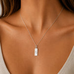 capricorn zodiac necklace - A close-up of a model wearing a delicate silver chain necklace with a small rectangular silver pendant engraved with the capricorn star sign line glyph.