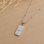 sterling silver chain necklace with a rectangle charm embossed with celestial design