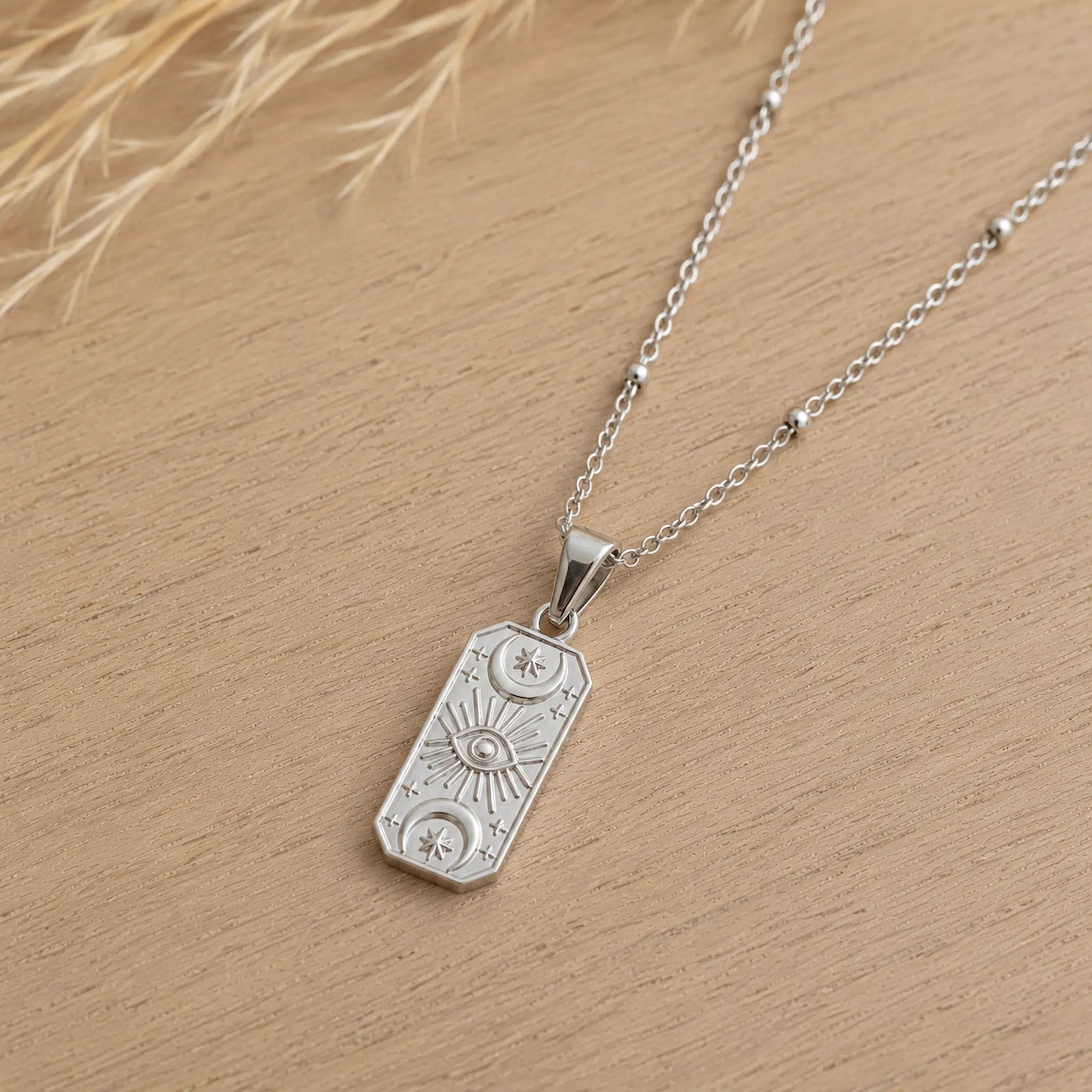 sterling silver chain necklace with a rectangle charm embossed with celestial design
