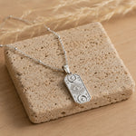 silver celestial charm pendant necklace laying on a natural stone