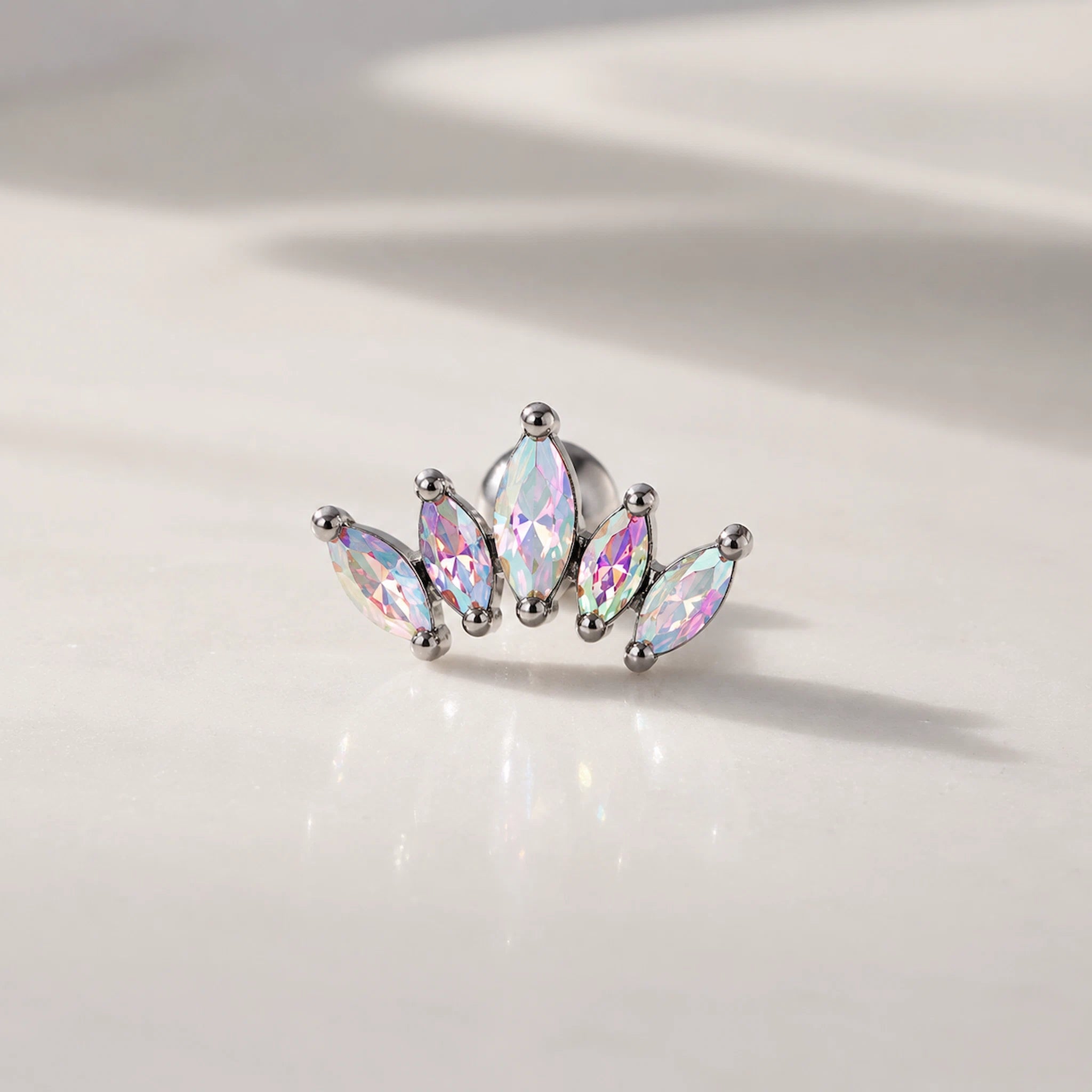 Silver earring with iridescent gemstones on a light background