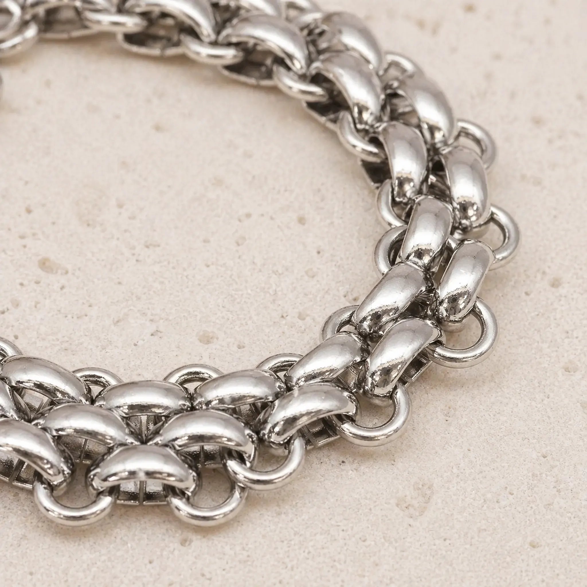 Close-up of a waterproof silver chunky chain bracelet on a light beige background