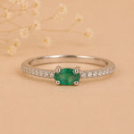 Sterling Silver Pave Ring with a oval shaped green faceted claw set emerald gemstone on a beige background