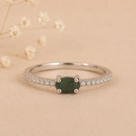 Sterling Silver Pave Ring with a oval shaped green faceted claw set emerald gemstone on a beige background