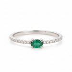 Classic Sterling Silver natural emerald ring - CZ Pave Stacking ring with a oval faceted claw set emerald gemstone on a beige background.