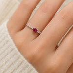 sterling Silver pave ring with a red ruby gemstone on a person's finger against a neutral background