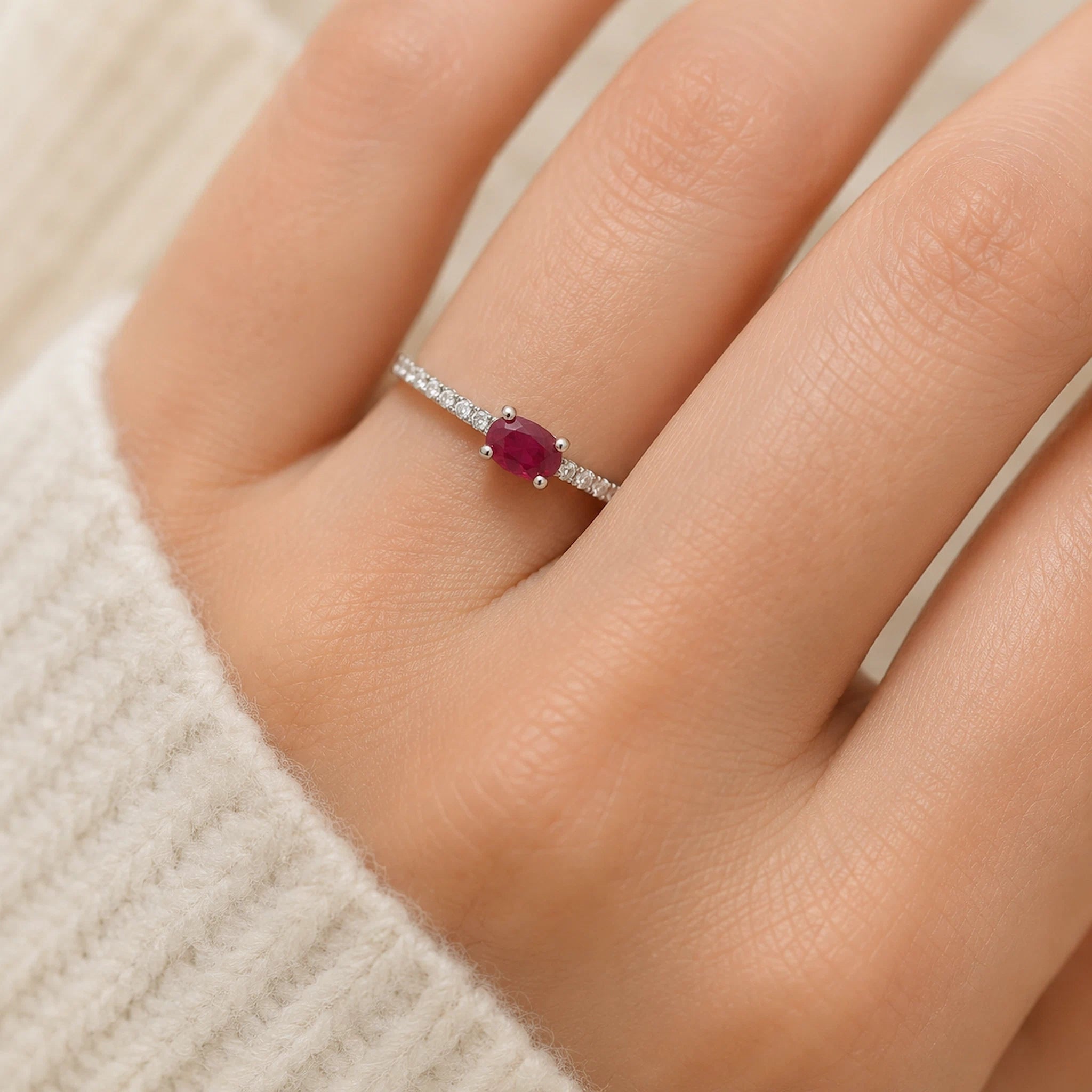 sterling Silver pave ring with a red ruby gemstone on a person's finger against a neutral background
