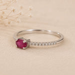 sterling Silver CZ pave style ring with a red ruby centre gemstone on a beige background