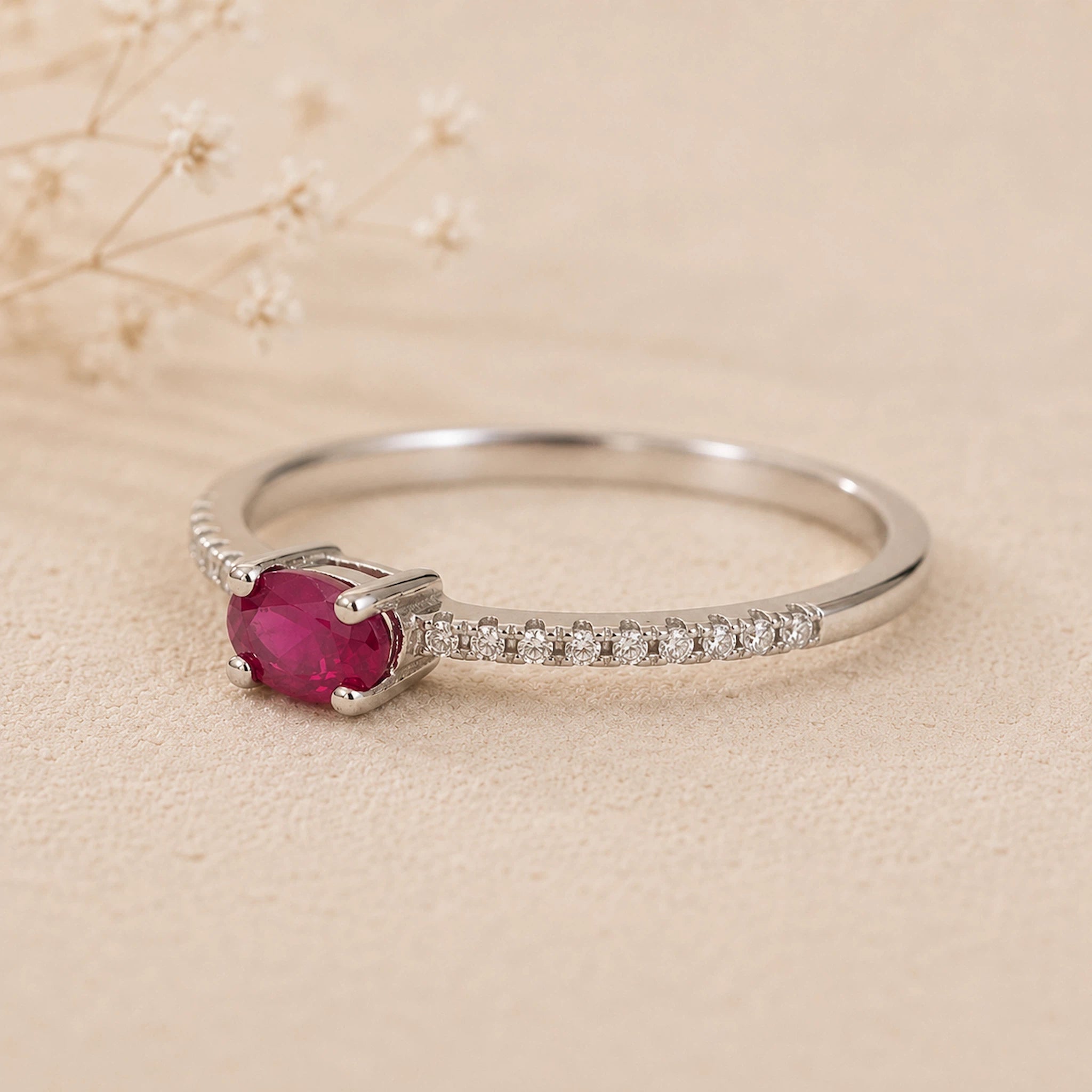 sterling Silver CZ pave style ring with a red ruby centre gemstone on a beige background