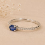 Sterling Silver pave stacking ring with a oval faceted claw set centre sapphire gemstone on a beige background