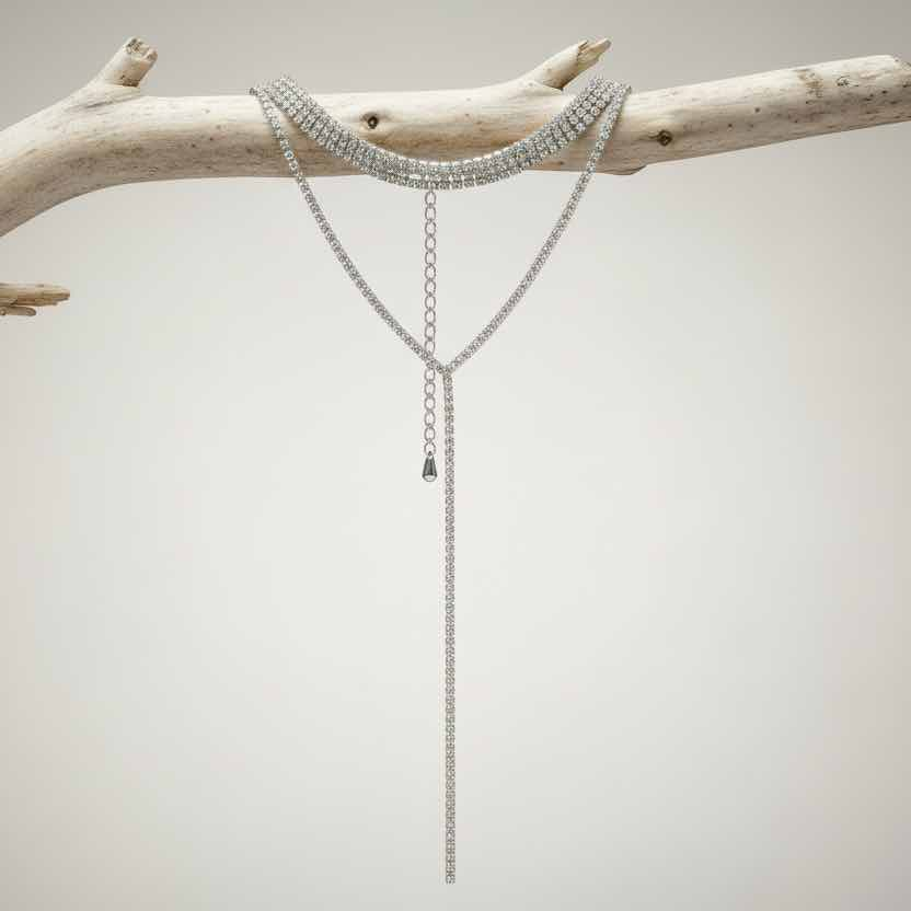 Silver chain necklace on a branch against a neutral background