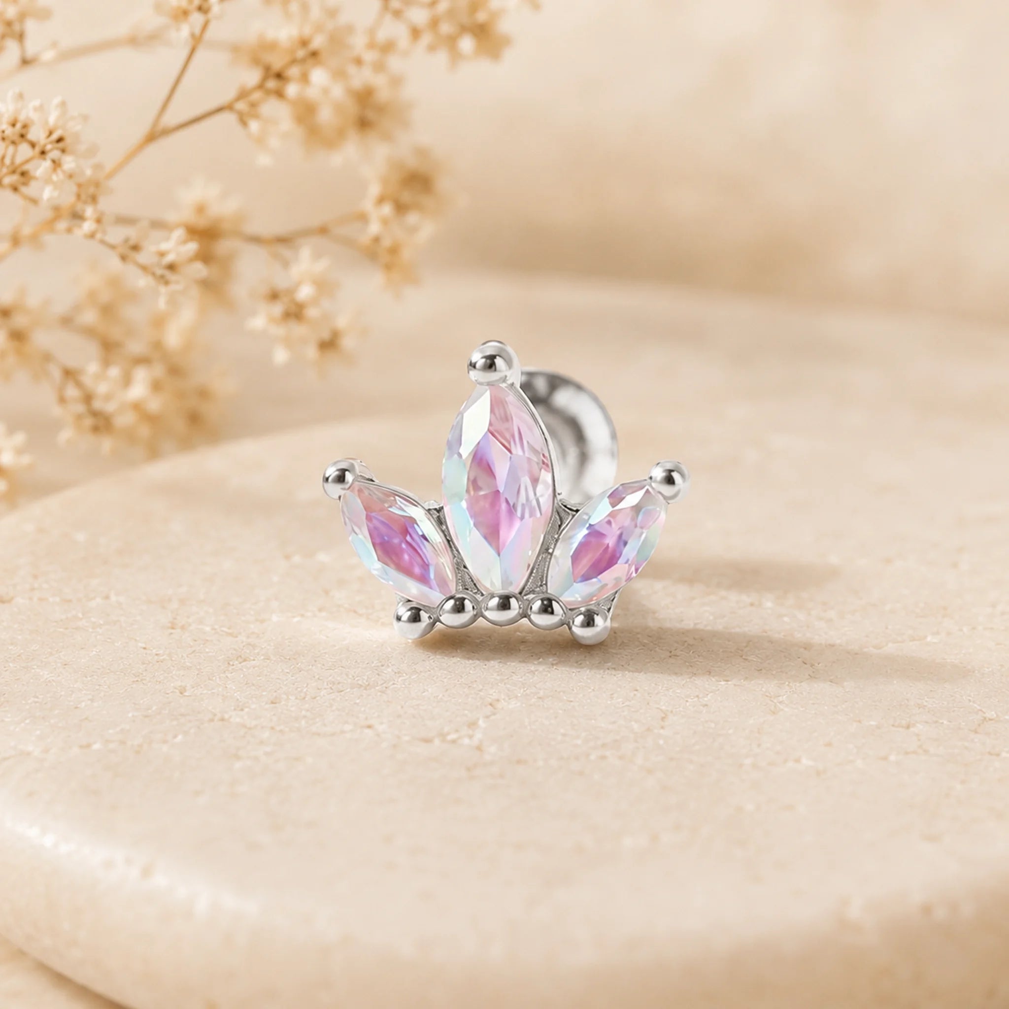 Silver earring with pink gemstones on a beige surface