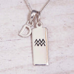 Sterling Silver D Initial and Aquarius Necklace on a fine silver chain against a light wooden background