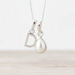 Sterling Silver necklace with 'D' initial pendant and teardrop-shaped mother of pearl charm on a light background