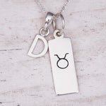 sterling Silver necklace with a 'D' initial pendant and a taurus zodiac star sign pendant on a light wooden background.
