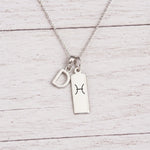sterling silver D initial Pisces Necklace on a fine silver chain against a light wooden background