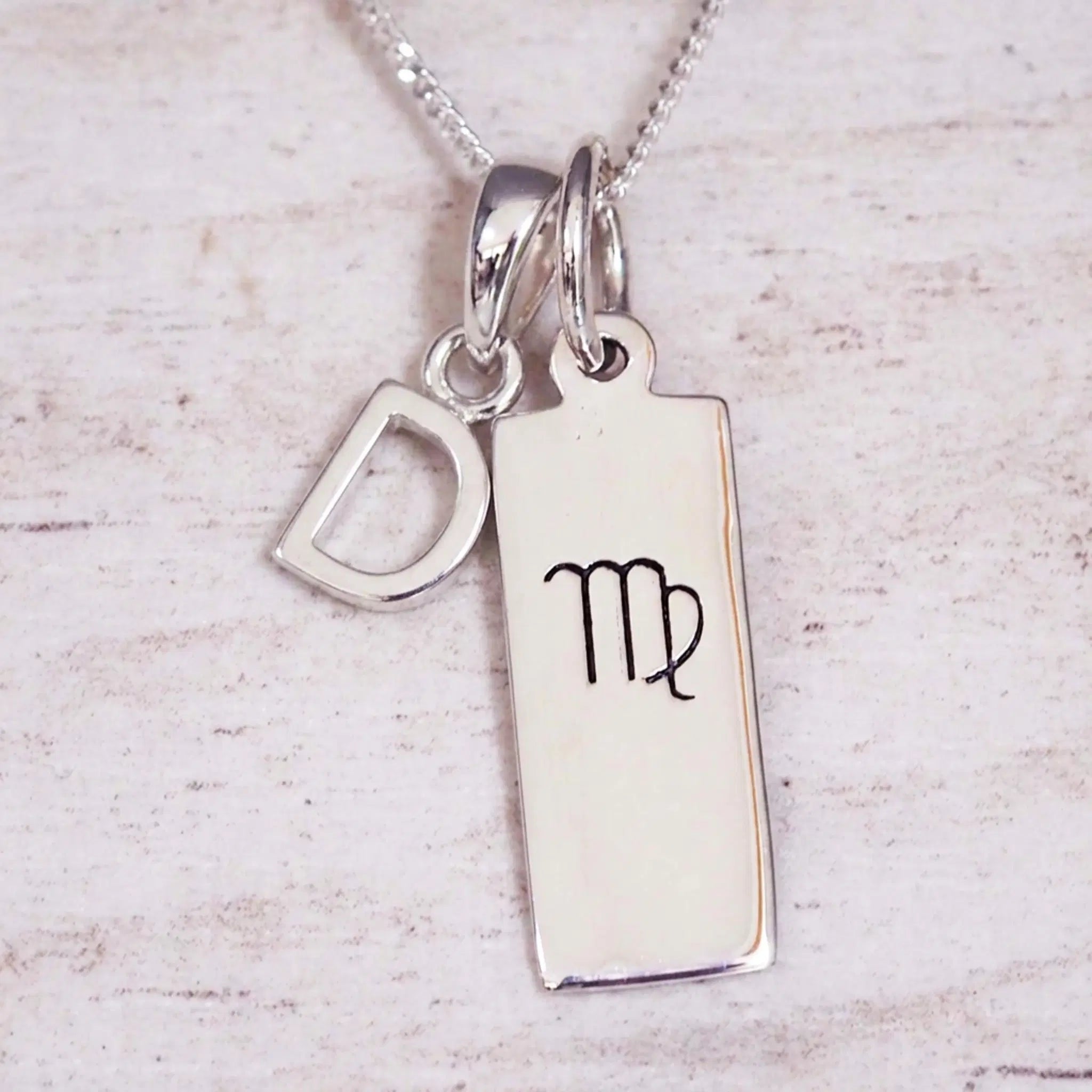 Sterling silver Virgo initial necklace with a letter D and engraved zodiac bar on light wood